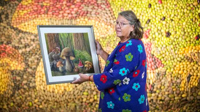 Konstnären Marianne Westerberg med originalmålningen och potatismosaiken i bakgrunden.