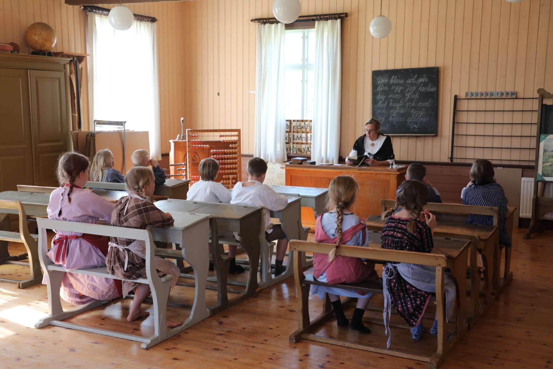 Undervisning i den gamla skolan, med en sträng fröken bakom katedern.