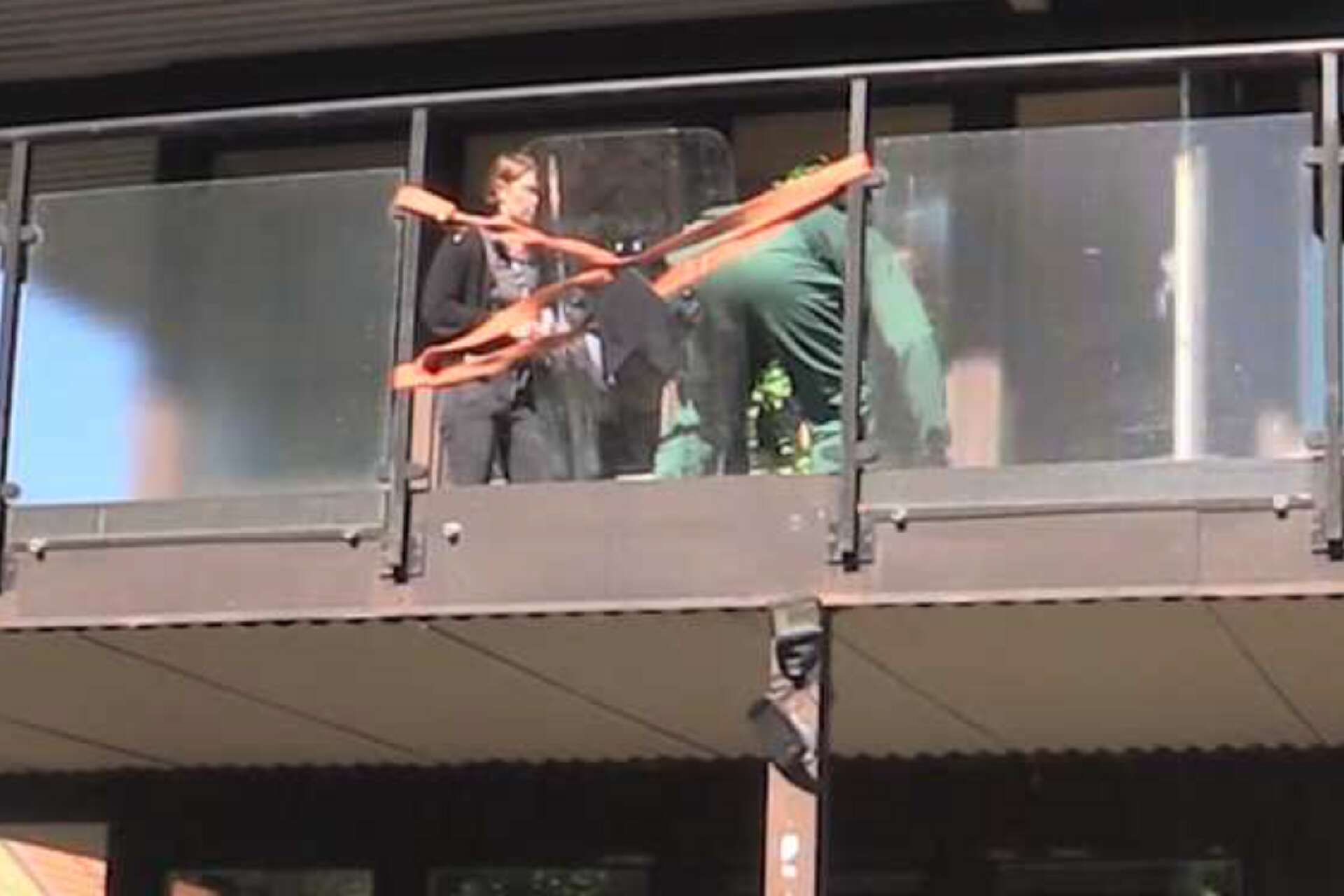 Den misstänkte 57-åringen visar under en rekonstruktion med polisen hur mannen föll ut från balkongen.