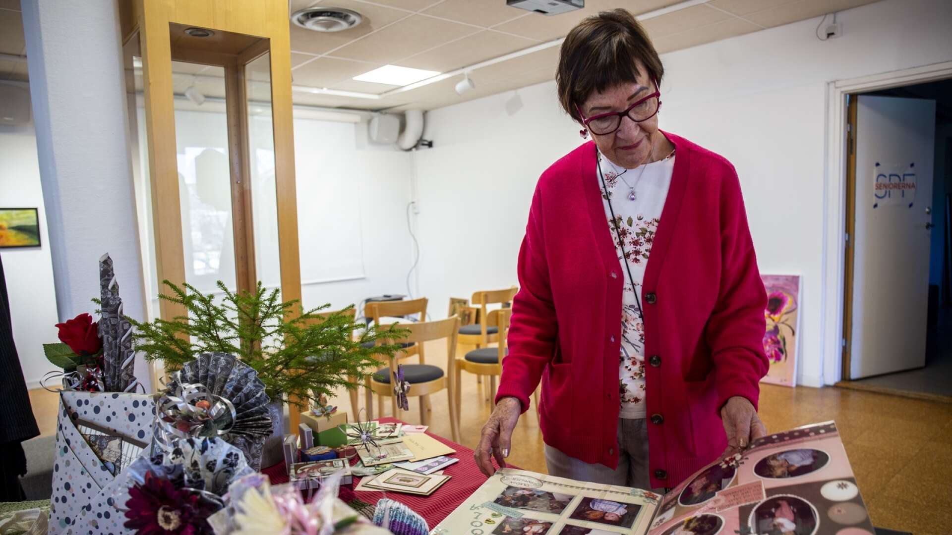 Lisette Lindenström, ordförande i SPF Seniorerna Åmåliterna, visar ett av utställningens många verk. Här har en medlem låtit sin pyssliga sida leva ut i form av en scrapbooking-bok. 