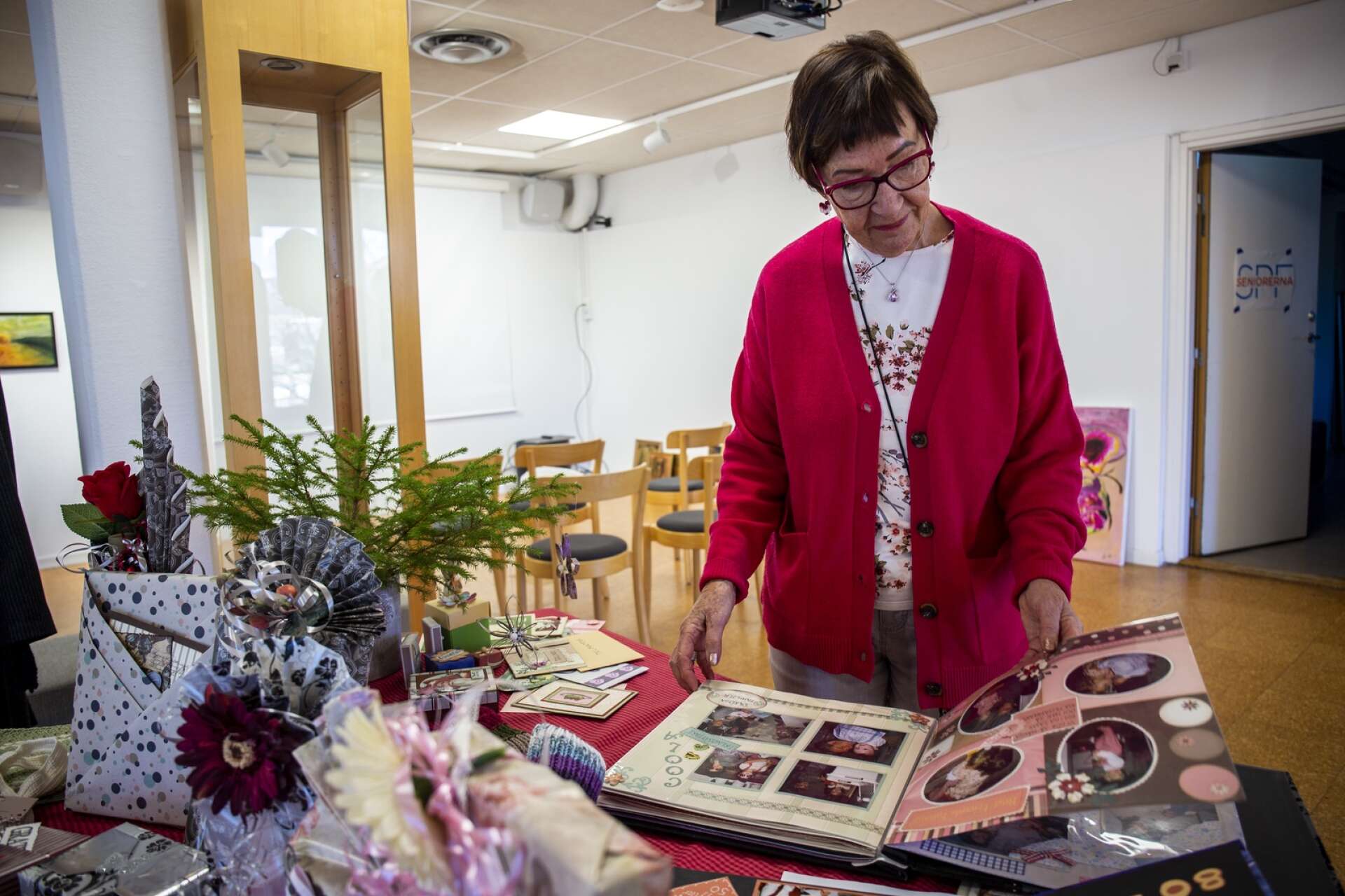 Lisette Lindenström, ordförande i SPF Seniorerna Åmåliterna, visar ett av utställningens många verk. Här har en medlem låtit sin pyssliga sida leva ut i form av en scrapbooking-bok. 