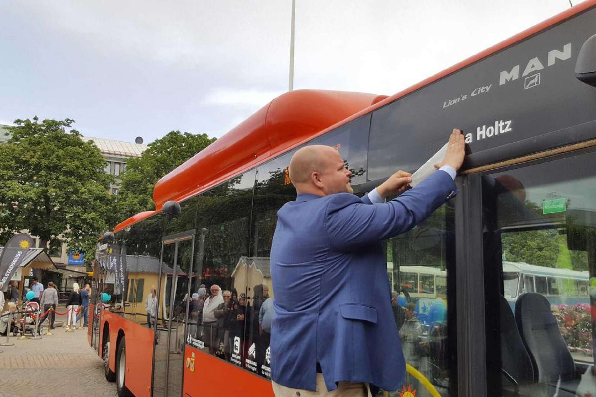 Peter Kullgren (KD), ordförande i stadsbyggnadsnämnden, drar bort tejp för att avslöja namnet på en av bussarna.