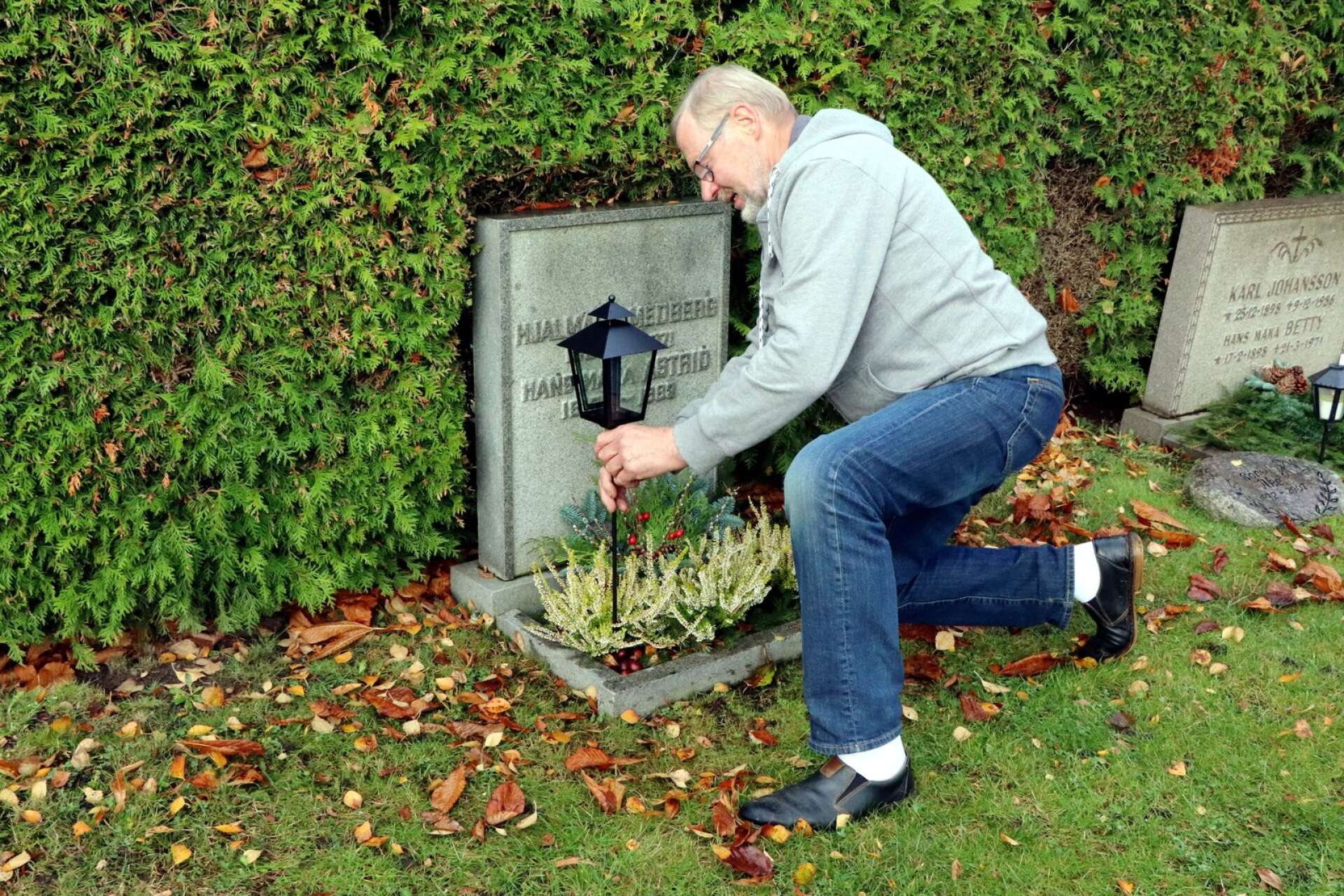 Olle Smedberg sätter upp lyktan på föräldrarnas grav på Hjo kyrkogård.
