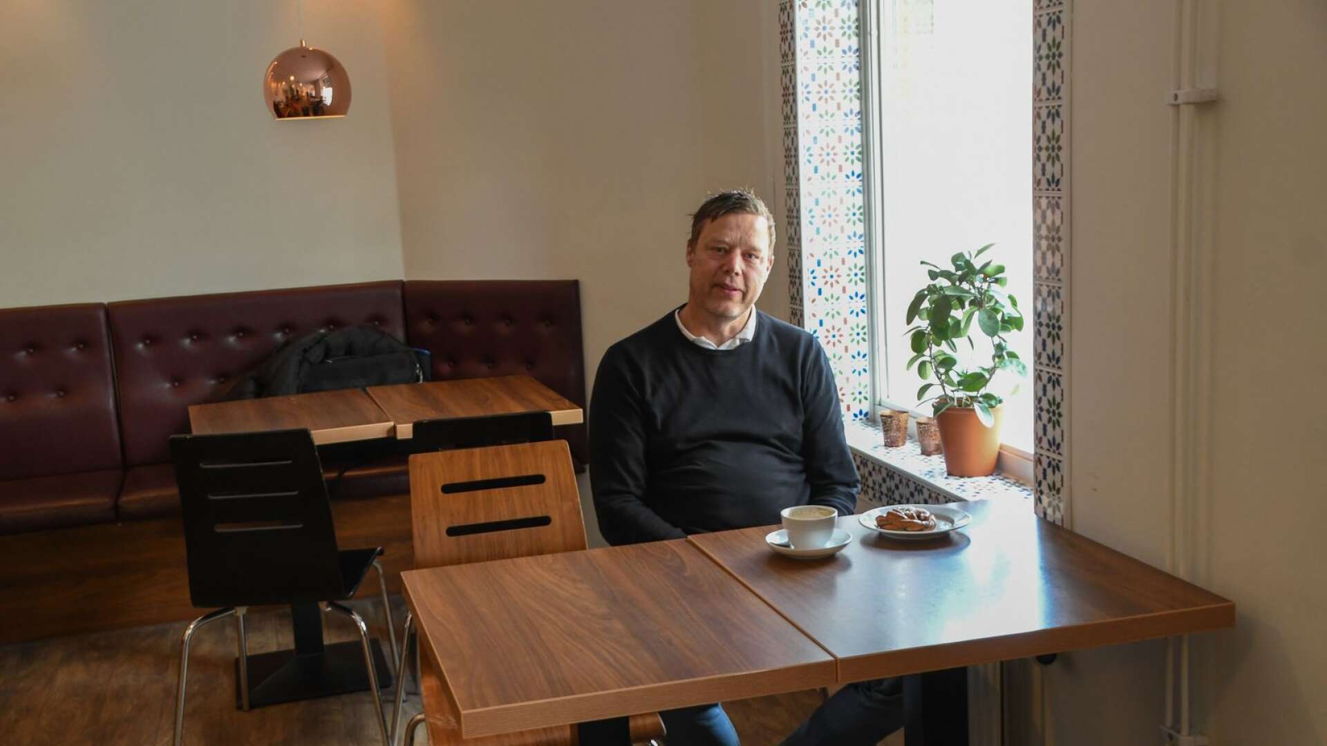 Joakim Stier tar en välbehövlig intervjukaffepaus med tillhörande bulle. I jobbet hastar han fram och tillbaka mellan två olika arbetsplatser.