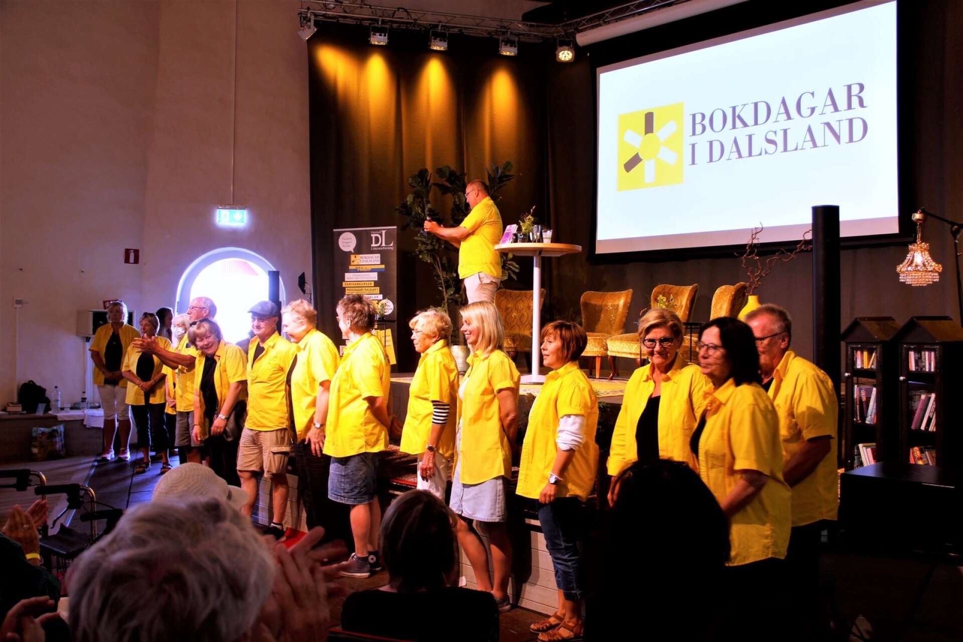 Bokdagar i Dalslands volontärer i gula skjortor uppradade i Gamla kyrkan i Åmål för ett stort tack för sitt arbete. I år anordnas sommarlitteraturfestivalen 26–30 juli.