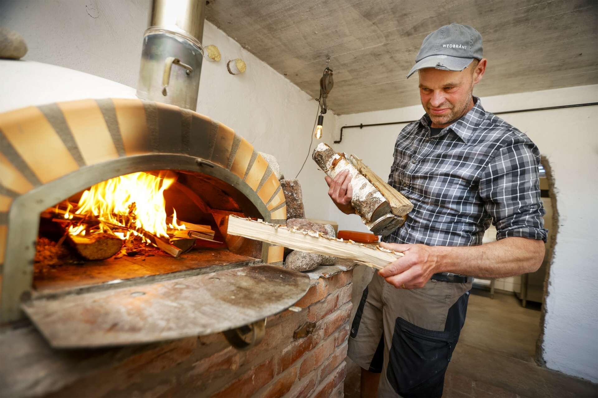 Thomas Peterson laddar in ved i ugnen, där de populära pizzorna gräddas.