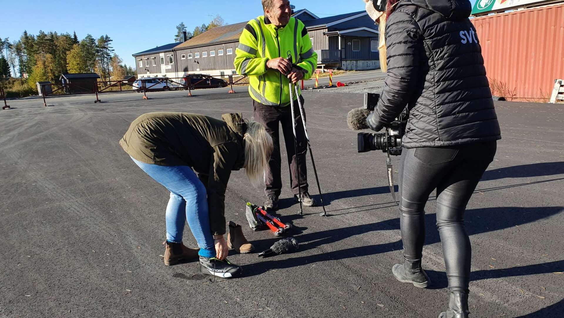 Jenny Eriksson filmar när Emma Schmidt tar på sig rullskidsutrustningen som Thore Berglund plockat fram.