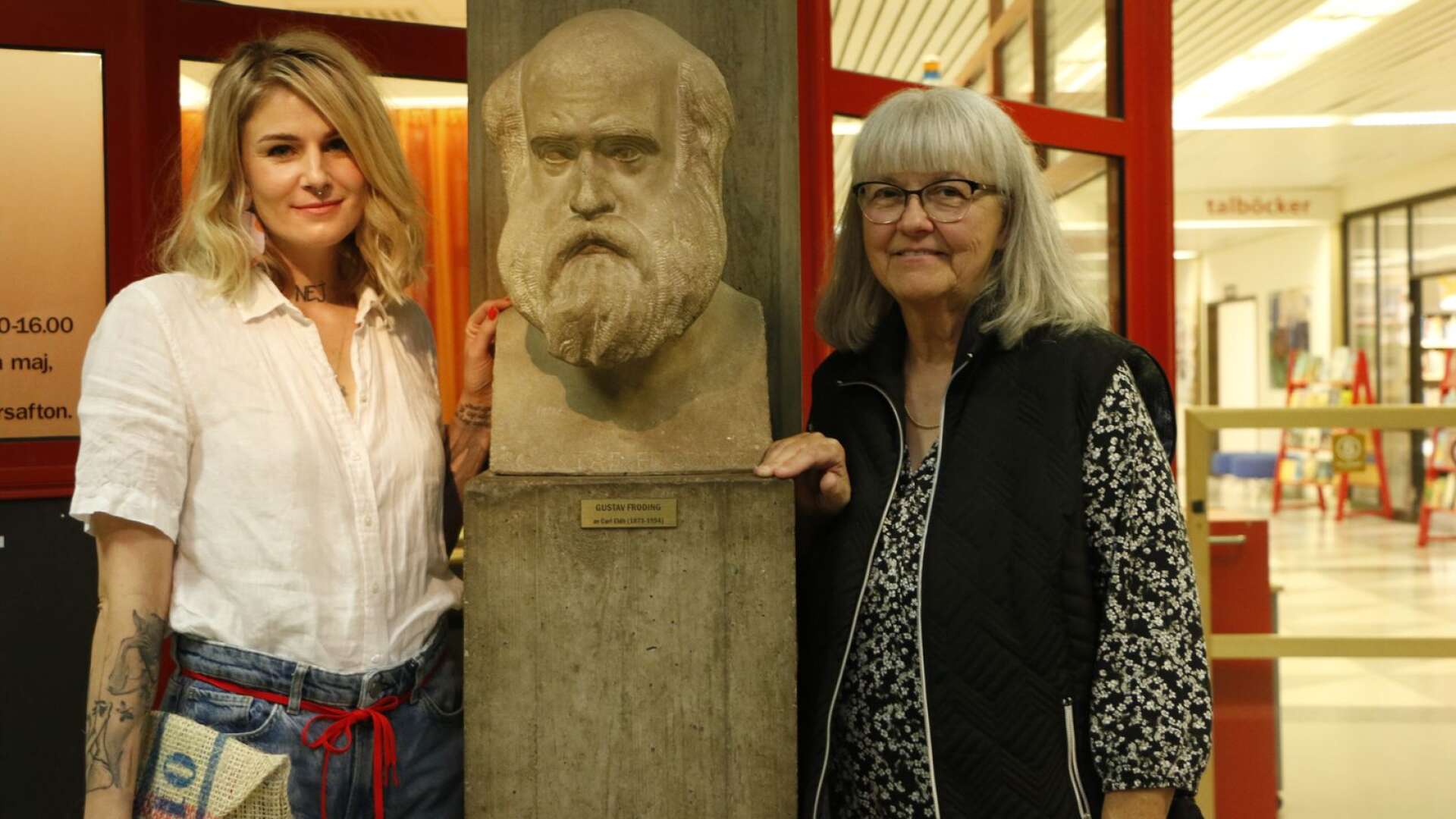 Marthe Hem och Berith Sande vid en skulptur av Gustaf Fröding på Karlstads stadsbibliotek. 
