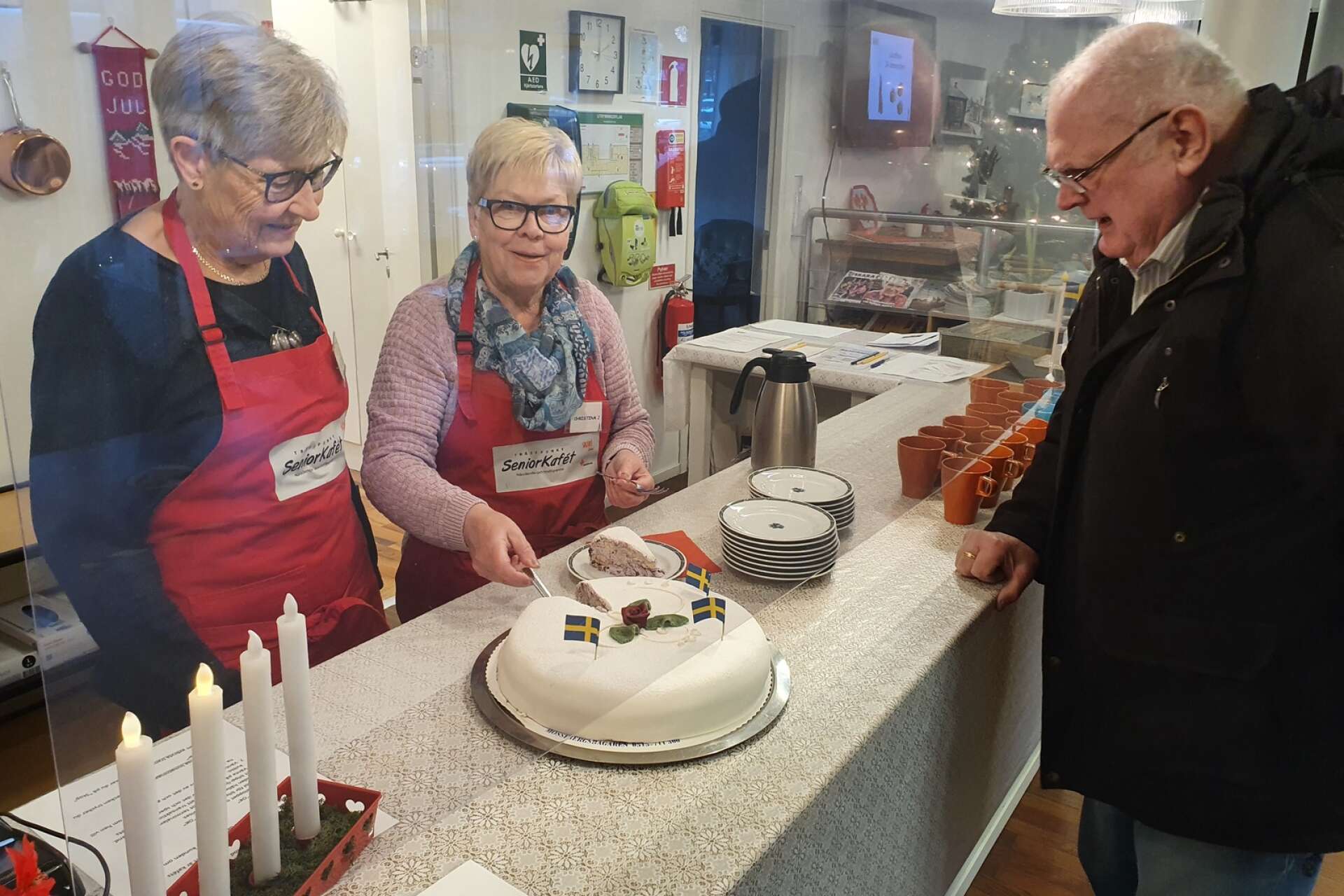 Berit Svensson och Christina Johansson serverar tårta till Göran Ivarsson från Axvall, som kommer varje gång det är öppet på Sockerbagaren.
