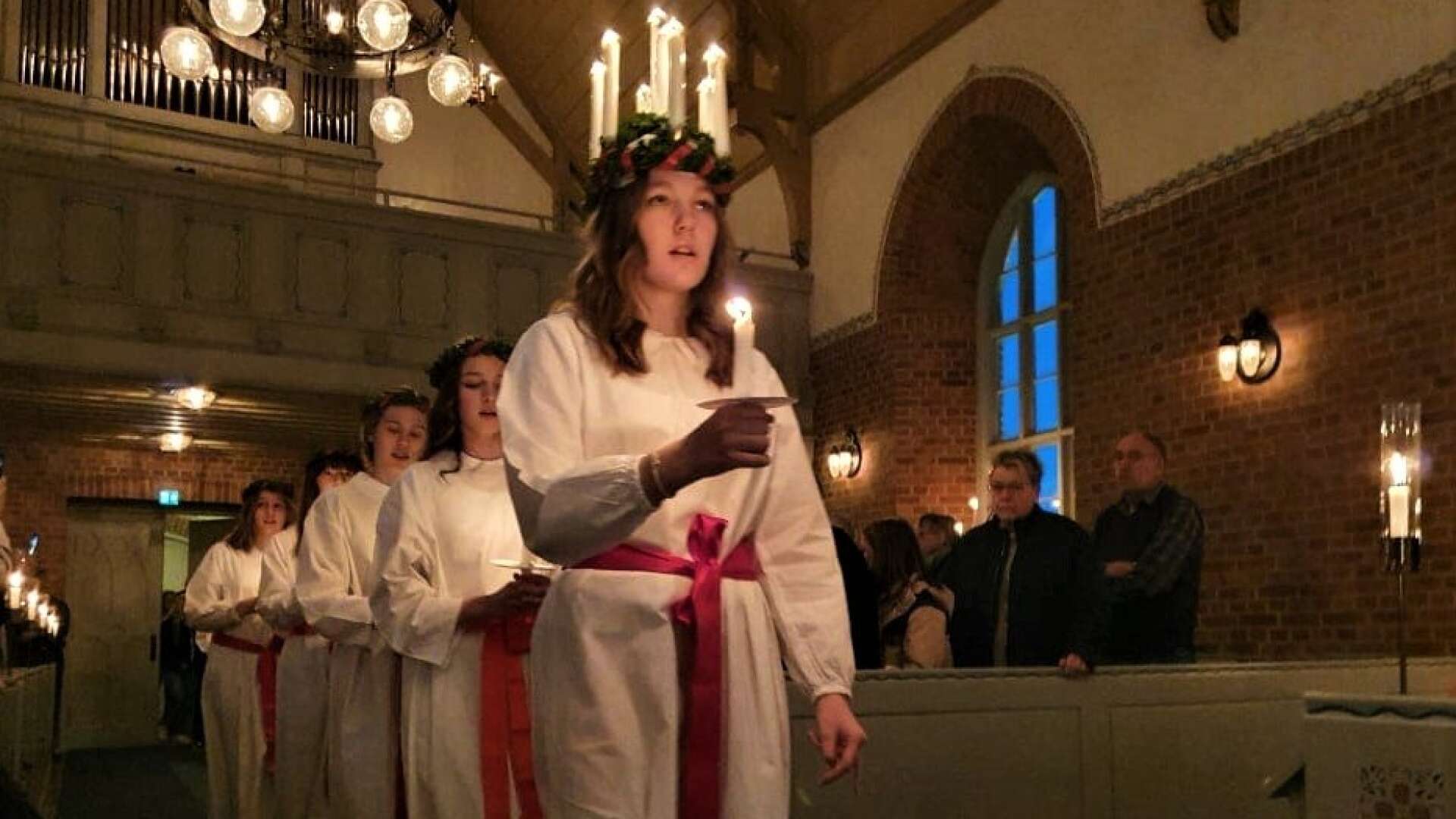 Thea Gunnarsson, Grästorps lucia 2021, skrider in i Grästorps kyrka med sina tärnor.