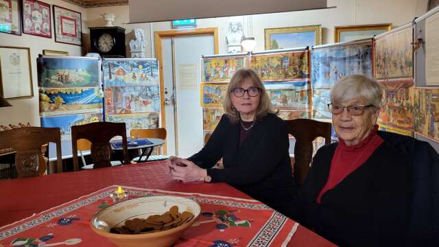 Hembygdsföreningens Margareta Nilars och museibesökaren Asta Andersson har slagit sig ner framför utställningen av klassiska julbonader.