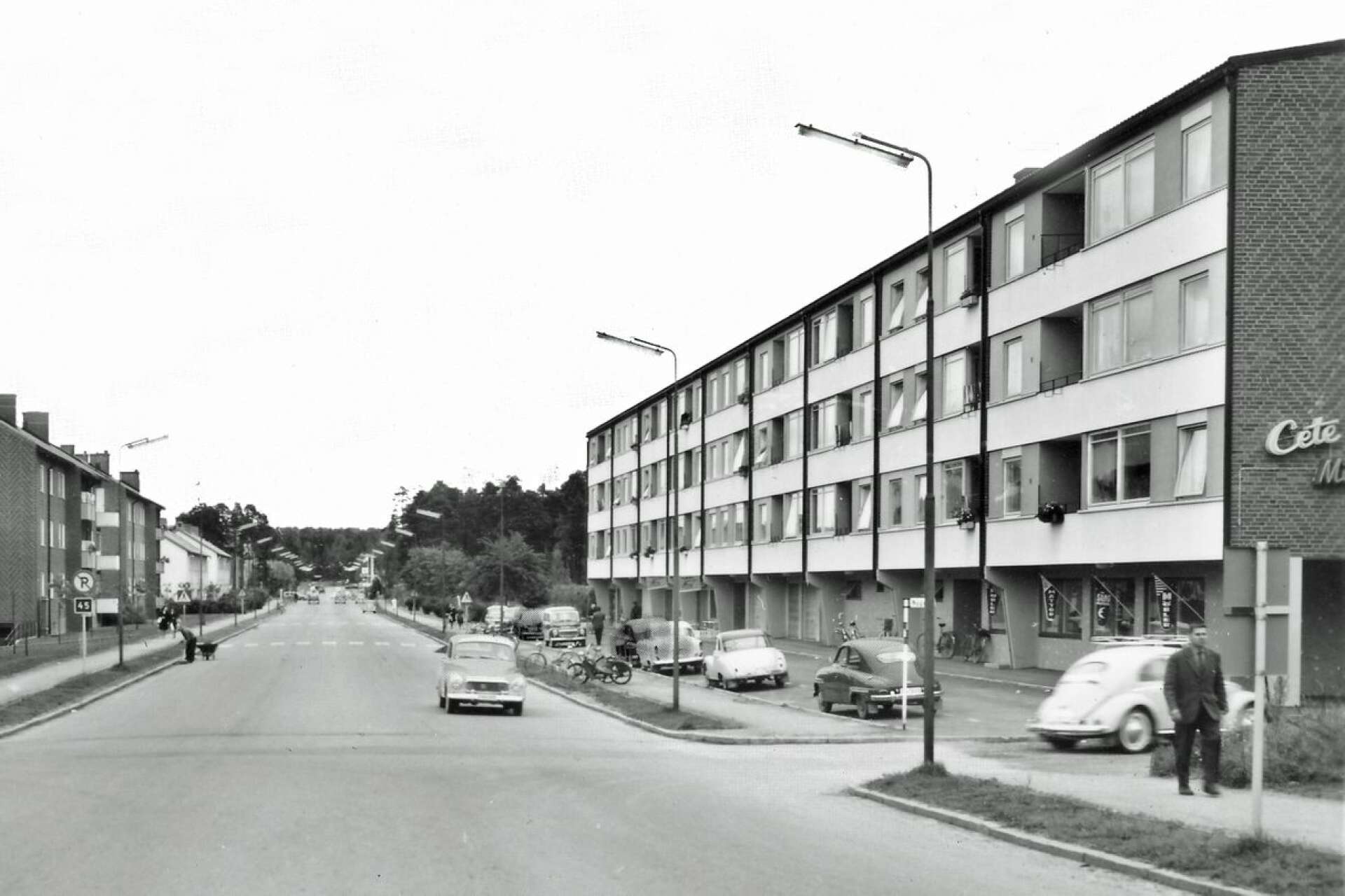 I det då nybyggda huset till höger på bilden öppnades 1 november 1960 livsmedelsbutiken Obe Livs. Närmast kameran ses Cete Möbler. Vallen till vänster hade byggts några år tidigare. Vänstertrafik var det fortfarande.  