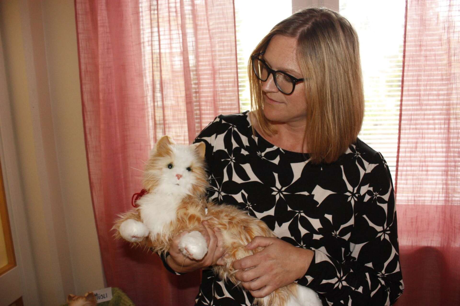 Anna Asplund med en katt framtagen för demensvård. Den kan jama, spinna, blinka och röra på huvudet. De är omtyckta på avdelningen. 