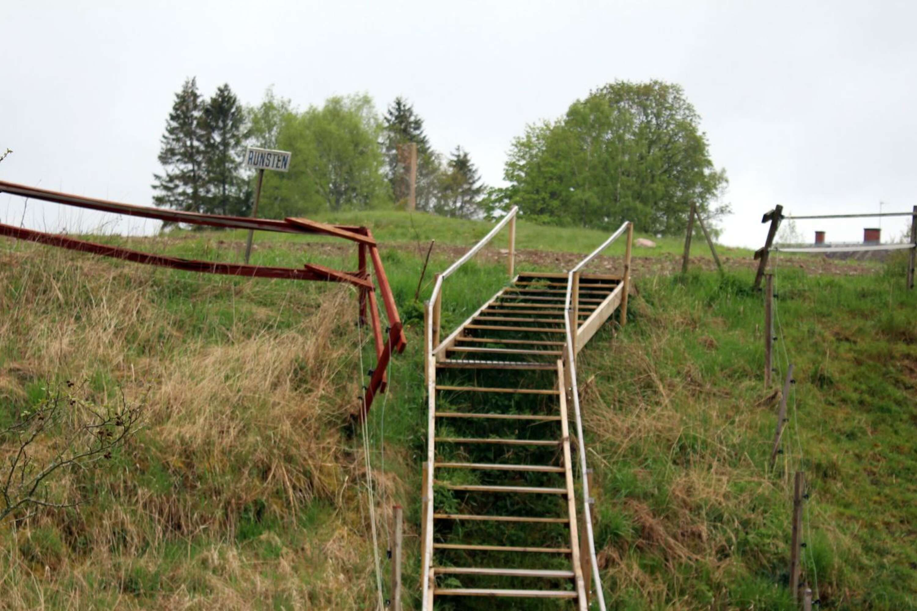 En trappa leder upp till kullen med runstenen.