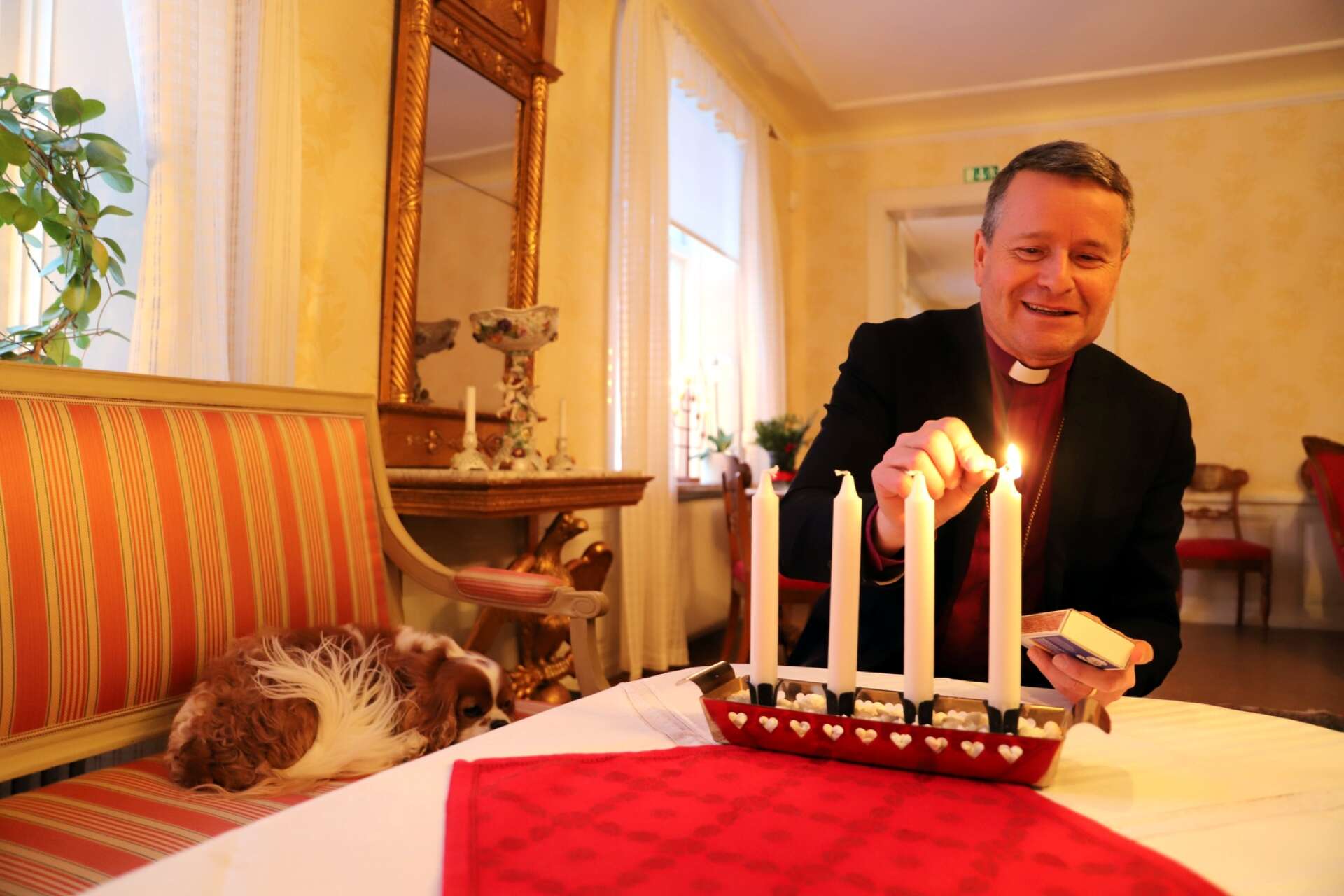 Biskop Sören Dalevi är aktuell med en ny bok med samlade krönikor på temat jul. Hunden Svante vilar lugnt medan husse tänder första adventsljuset.