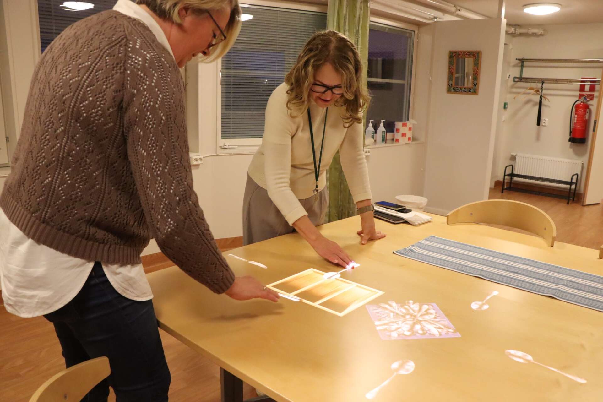 Helena Lundgren Kiss och Susanne Ljungberg provar ett spel där man ska putsa bestick och lägga i lådor. 