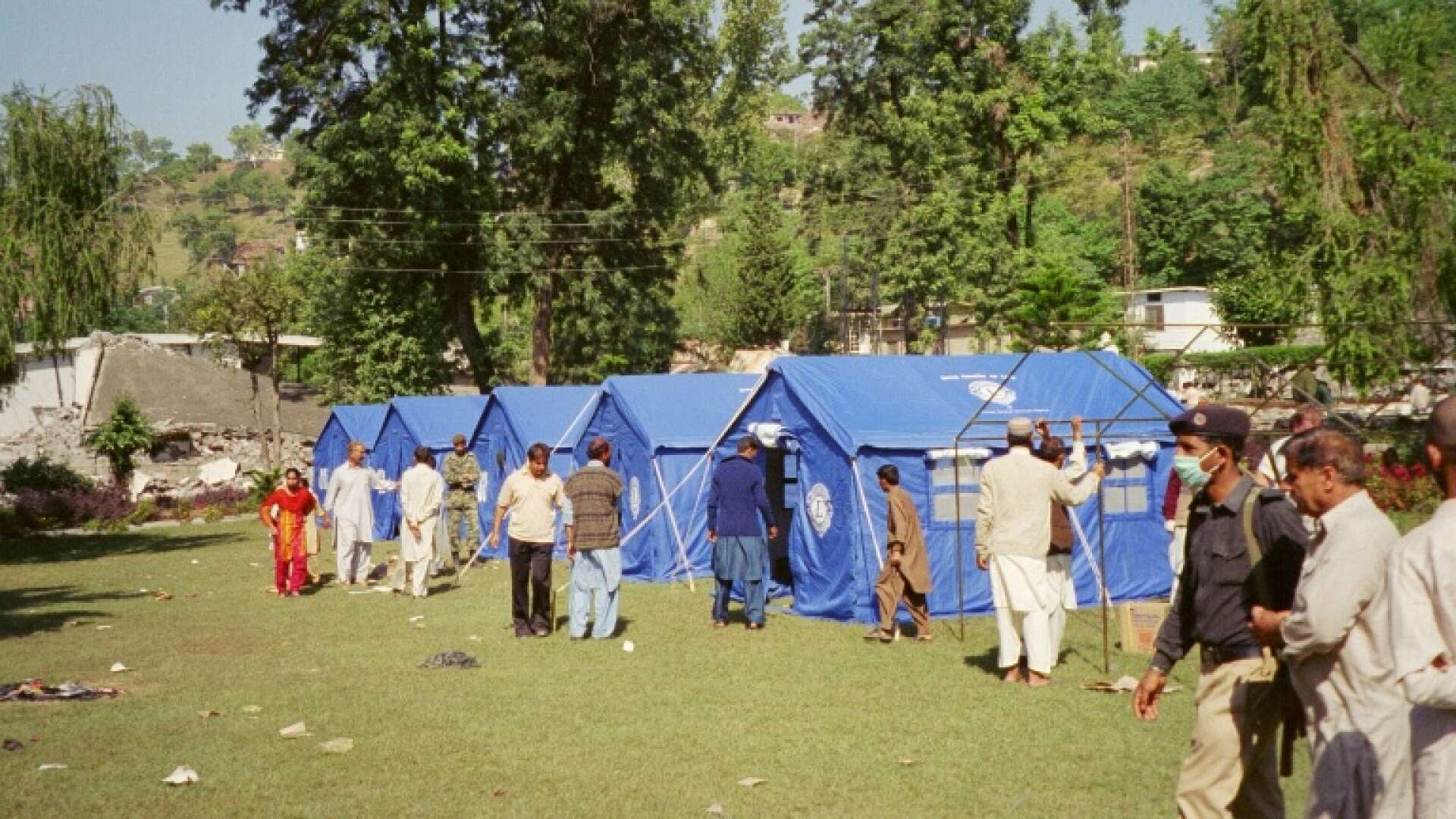 Militären och lokalbefolkningen bygger upp Lions tält i Jalalabad Park, Muzafarrabad sex dagar efter den stora jordbävningen i Pakistan 2005.  På området sattes totalt 75  tält från Lions och flera svenska militärtält upp.