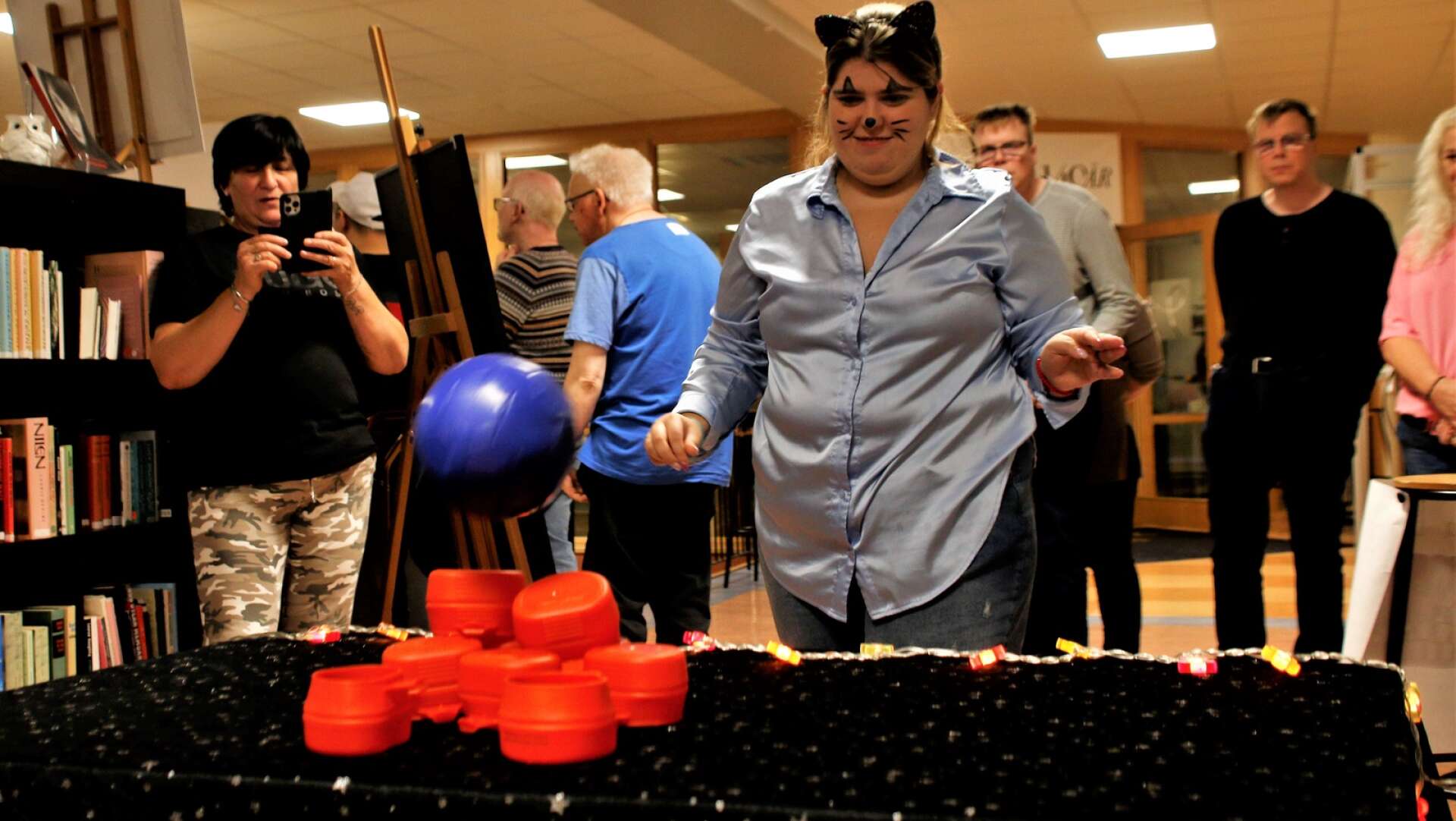 Anita Elshani tar en boll. Hon siktar och kastar och burkarna på bordet far i golvet. 