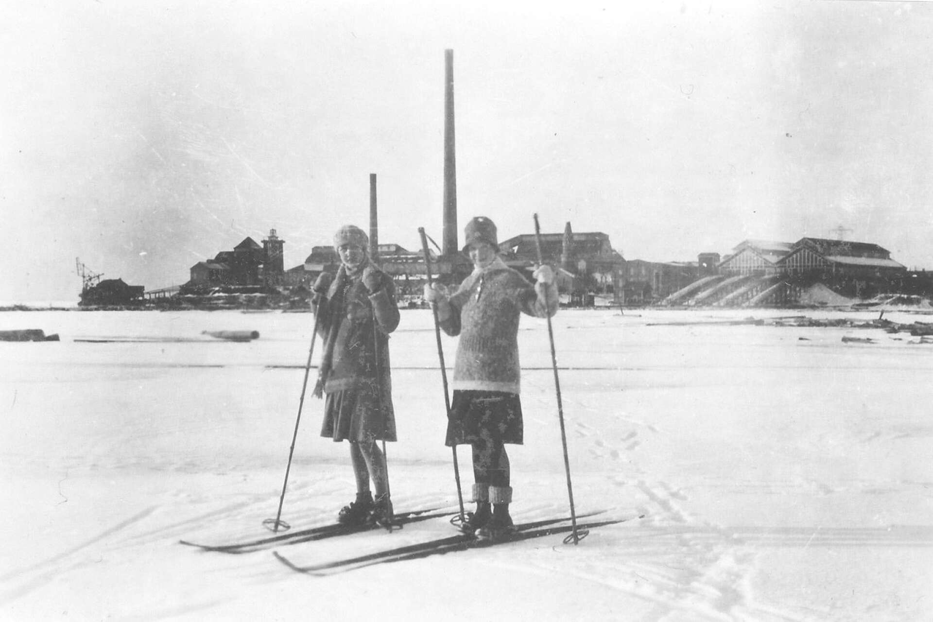 Flickor på skidor på isen utanför fabriken i Skoghall, fotoår omkring 1920-30. 