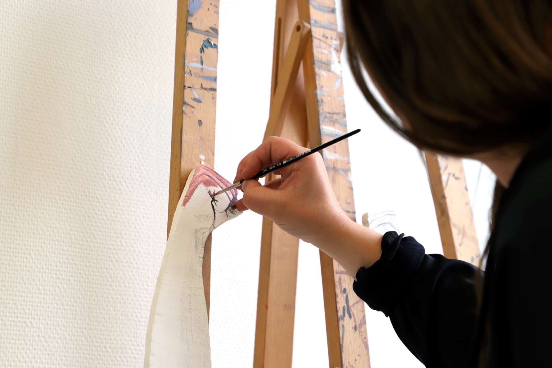 En knuten näve ska få sin kulör. Amanda Karlsson målar med oljefärger på furuplywood.