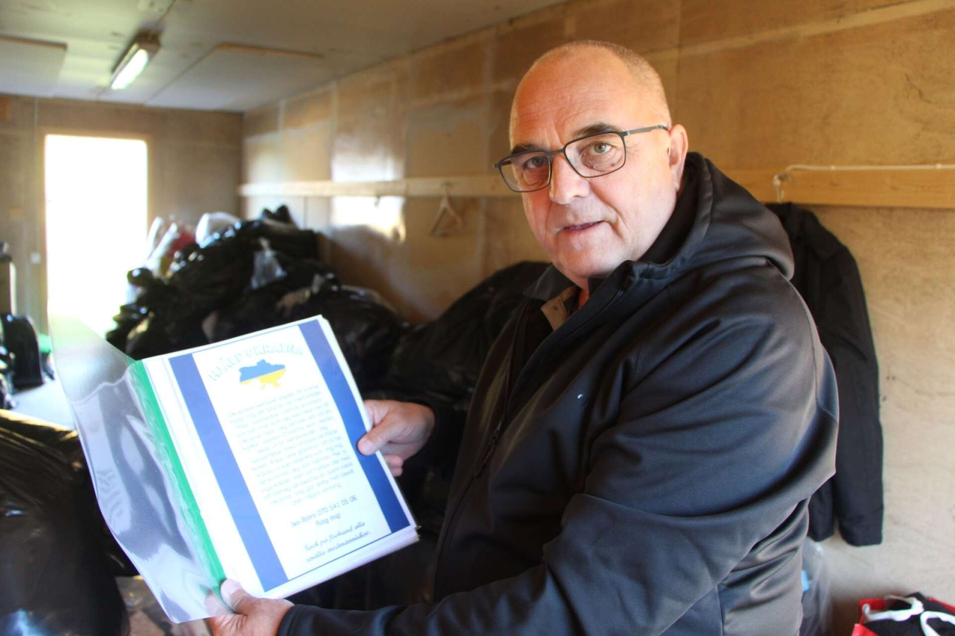 Jan Björn med egna flygbladet ”Hjälp Ukraina” i lokalen med kanske hundra säckar kläder, som han kör till Ukraina på torsdag.
