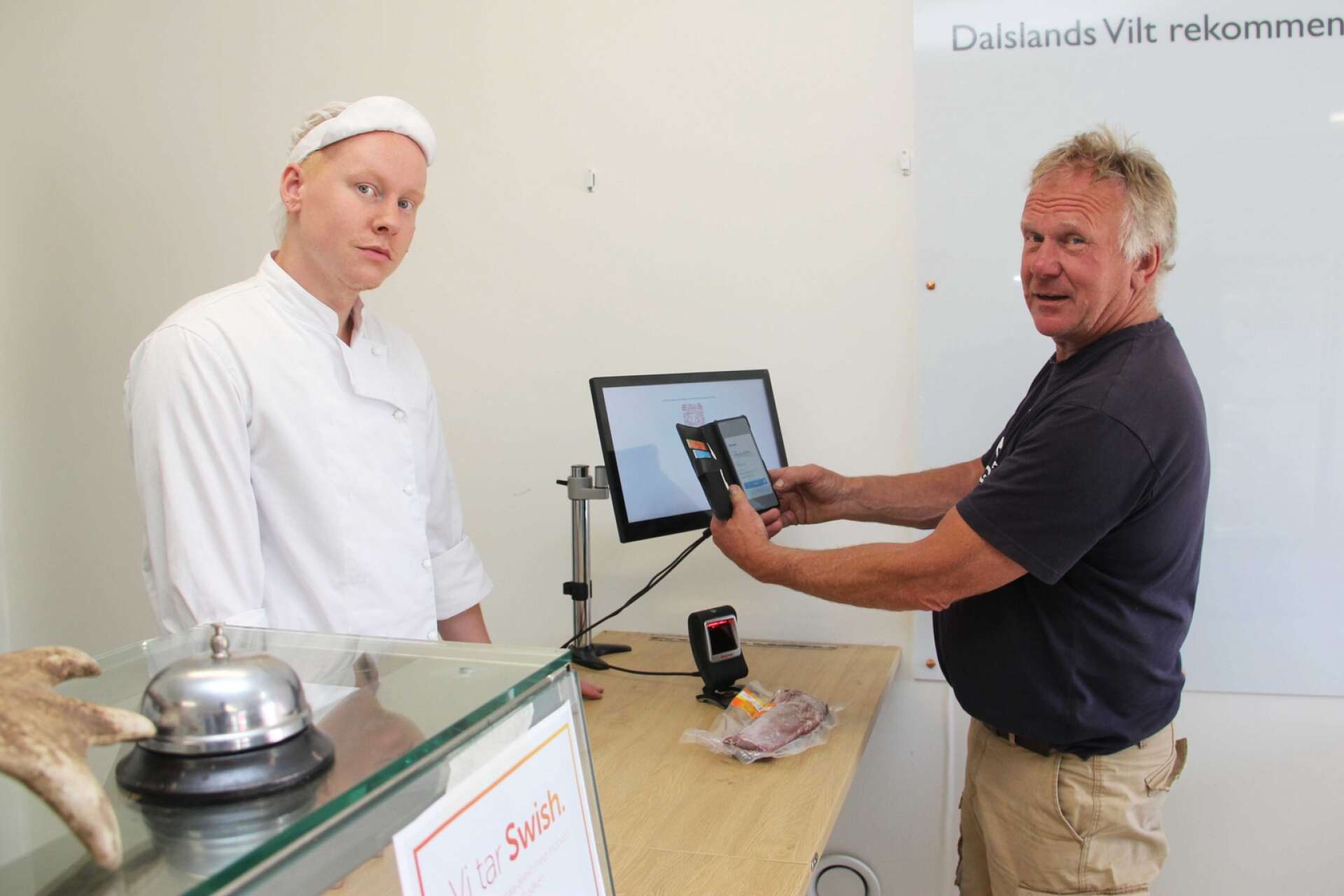 Kjell Johansson, vd Dalslands Vilt, demonstrerar den nyinstallerade tekniken vid disken där Johan Andersson servar kunder.