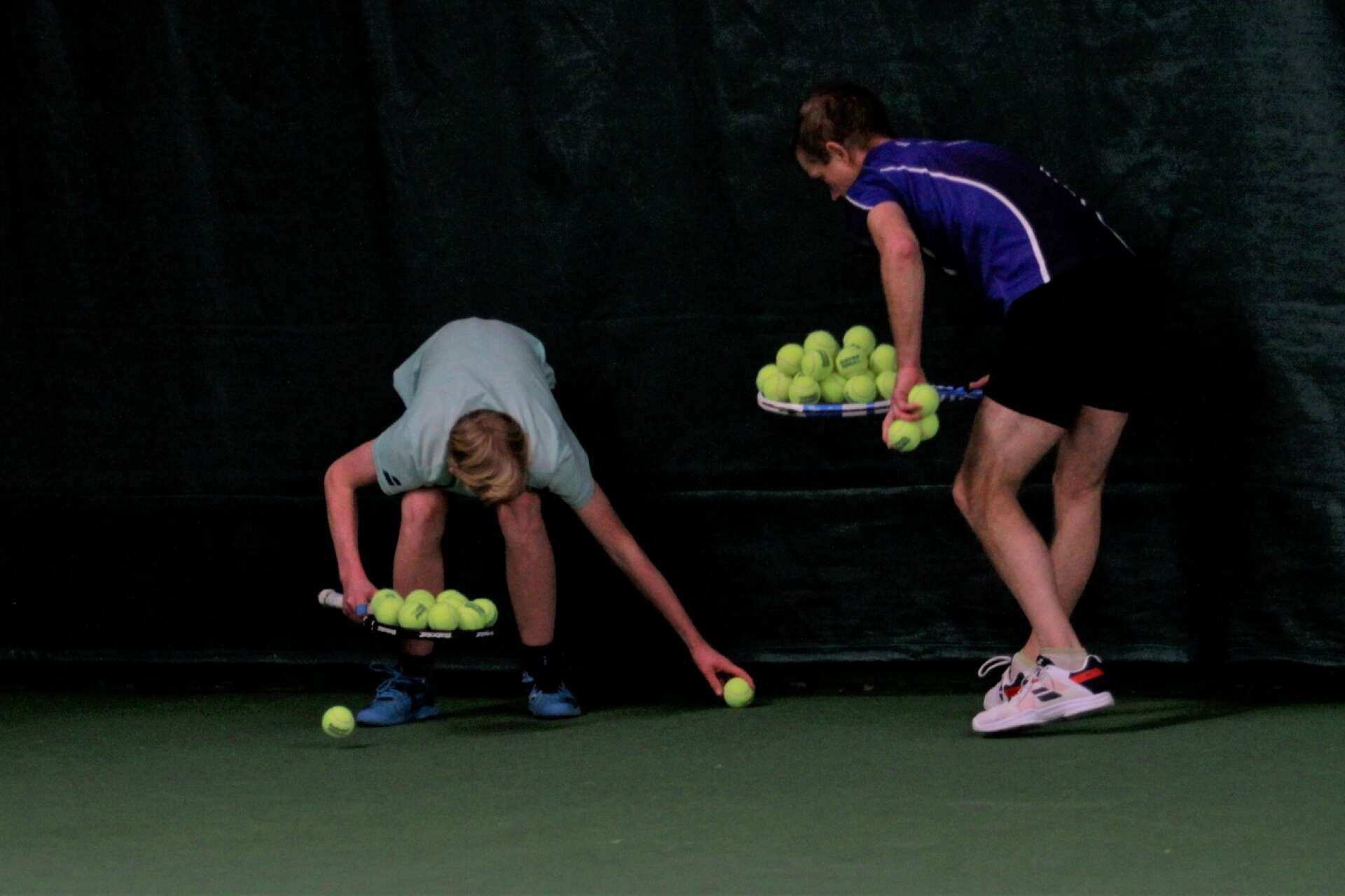 Träning i tennishallen. Bruno och Håkan Jonsson samlar ihop bollarna efter en övning.