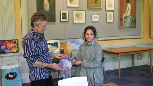 Alina Kheti har lämnat över sitt konstverk till Lars Törnell inför utställningen på biblioteket.