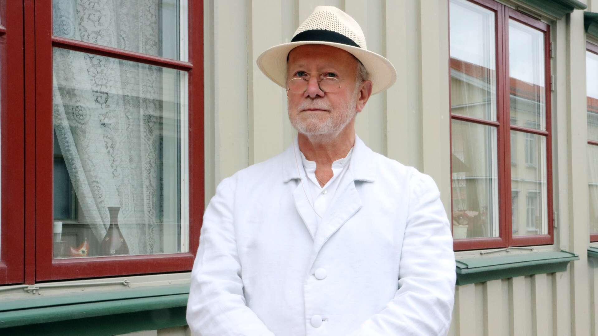 Öivind Åsberg står vid huset där Gustaf Fröding bodde i sina ungdomsår under en av hans Frödingvandringar i Kristinehamn.