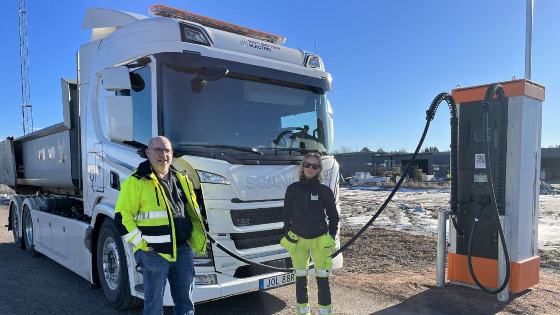 Mikael Lind, transportledare och Saga Kvarnström, chaufför, framför den eldrivna lastbilen som står på laddning.