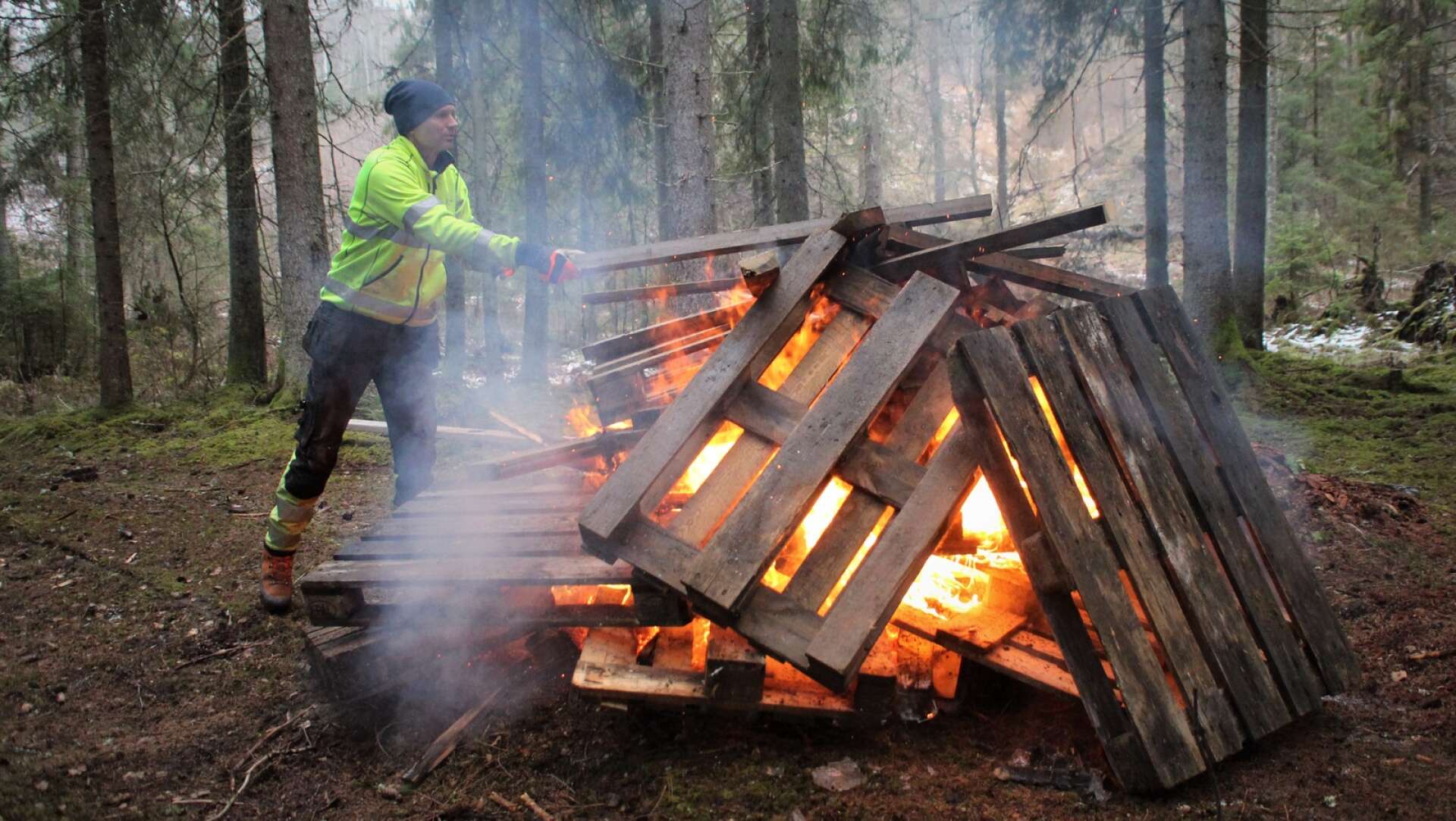 Kommunbiolog Oscar Säwström lägger mer brädor på brasan när hinderbanan för motorfordon som någon byggt i norra Bullerdalen eldades upp.