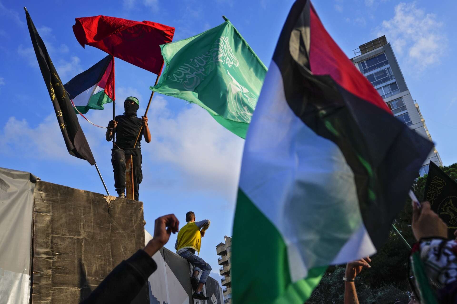 En man håller upp Palestinas och Hamas flaggor vid en demonstration i Beirut. Arkivbild.