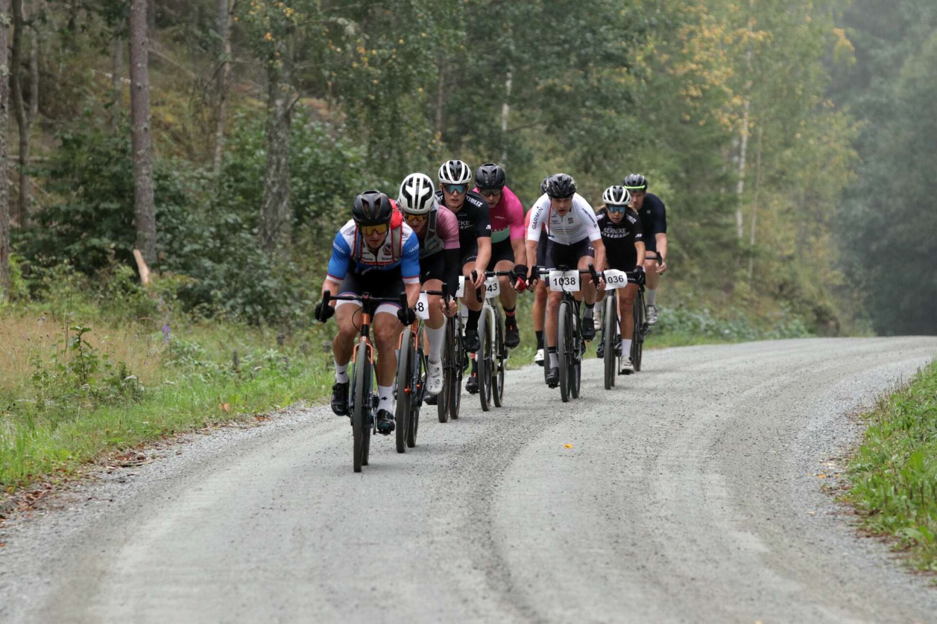 Camp Dalsland, Gravel Race 2023. Ett gäng cyklister i efter depån i Herrenäs, näst sist i klungan syns damsegraren Therese Andersson.