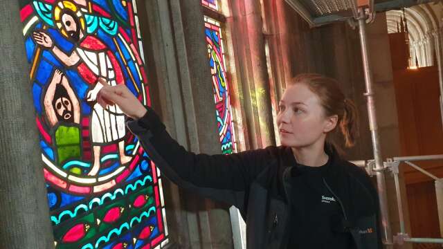 Glasmålerikonservator Amanda Sörhammar pekar ut de olika delarna på Evangeliefönstret. Svart är generellt sett bly.