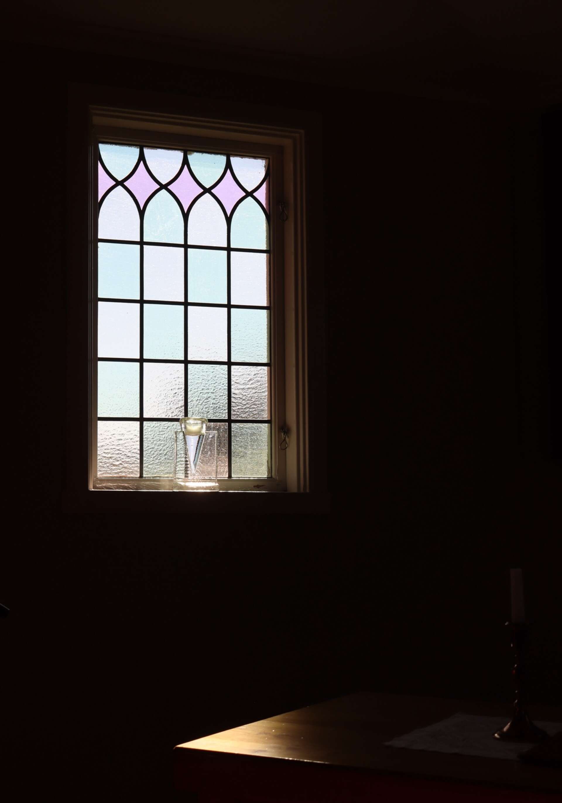 Ett av två blyinfattade fönster längst fram i kyrkorummet. 