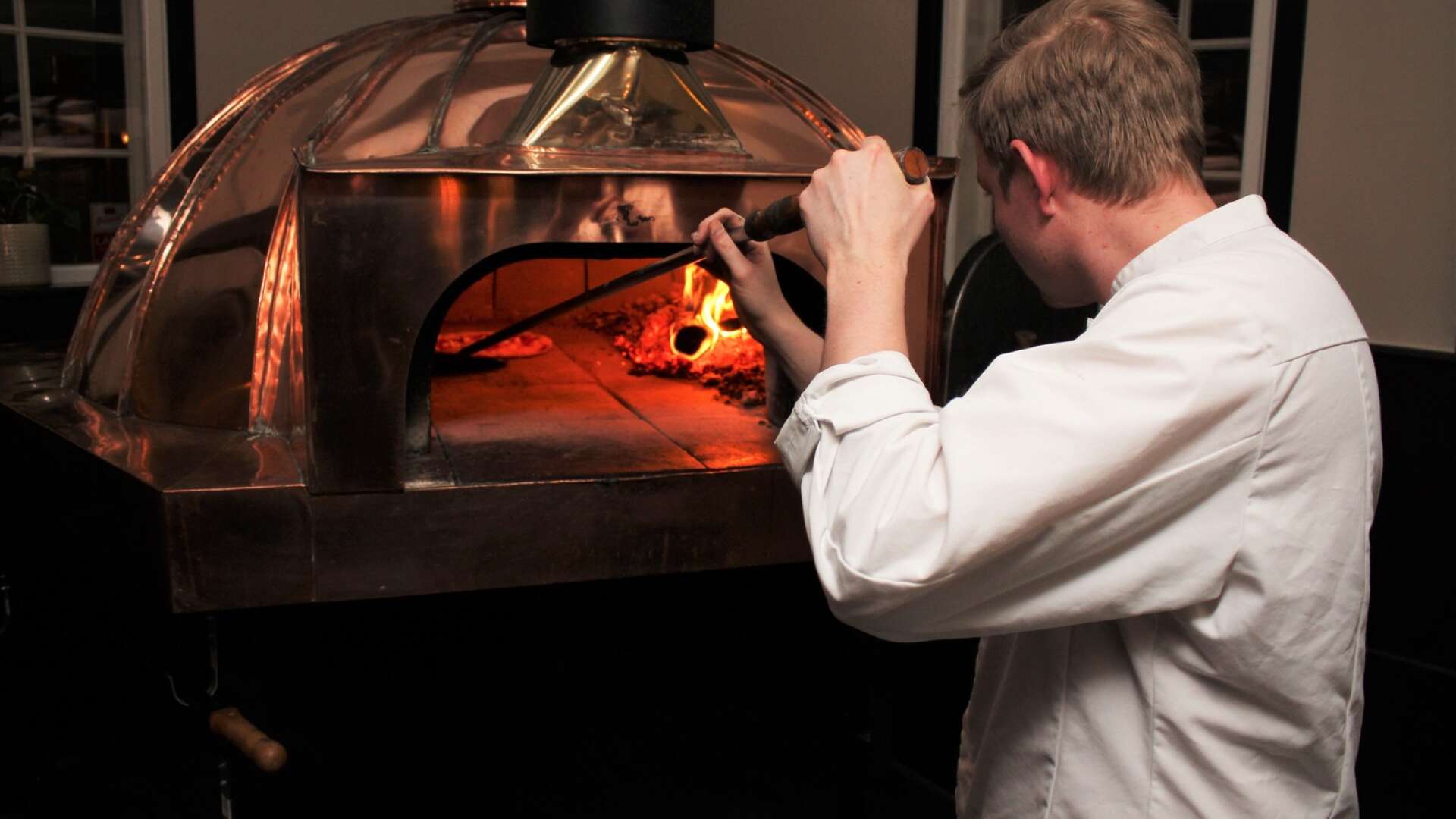 Markus Enocksson skyfflar in ännu en pizza i den nya vedugnen. Det tar inte många sekunder innan pizzan är klar i den 500-gradiga värmen så det gäller att vara på tårna och snurra pizzan ofta.