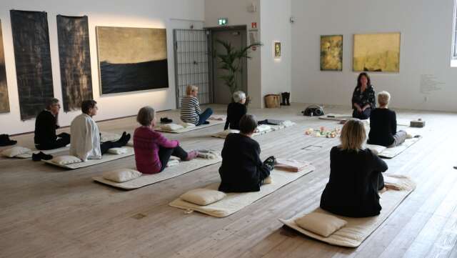 Yoga på mjuka ullmattor i konstmuseets luftiga utställningshall.