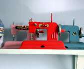 Symaskiner i leksaksversion samsas på en hylla i ateljén.