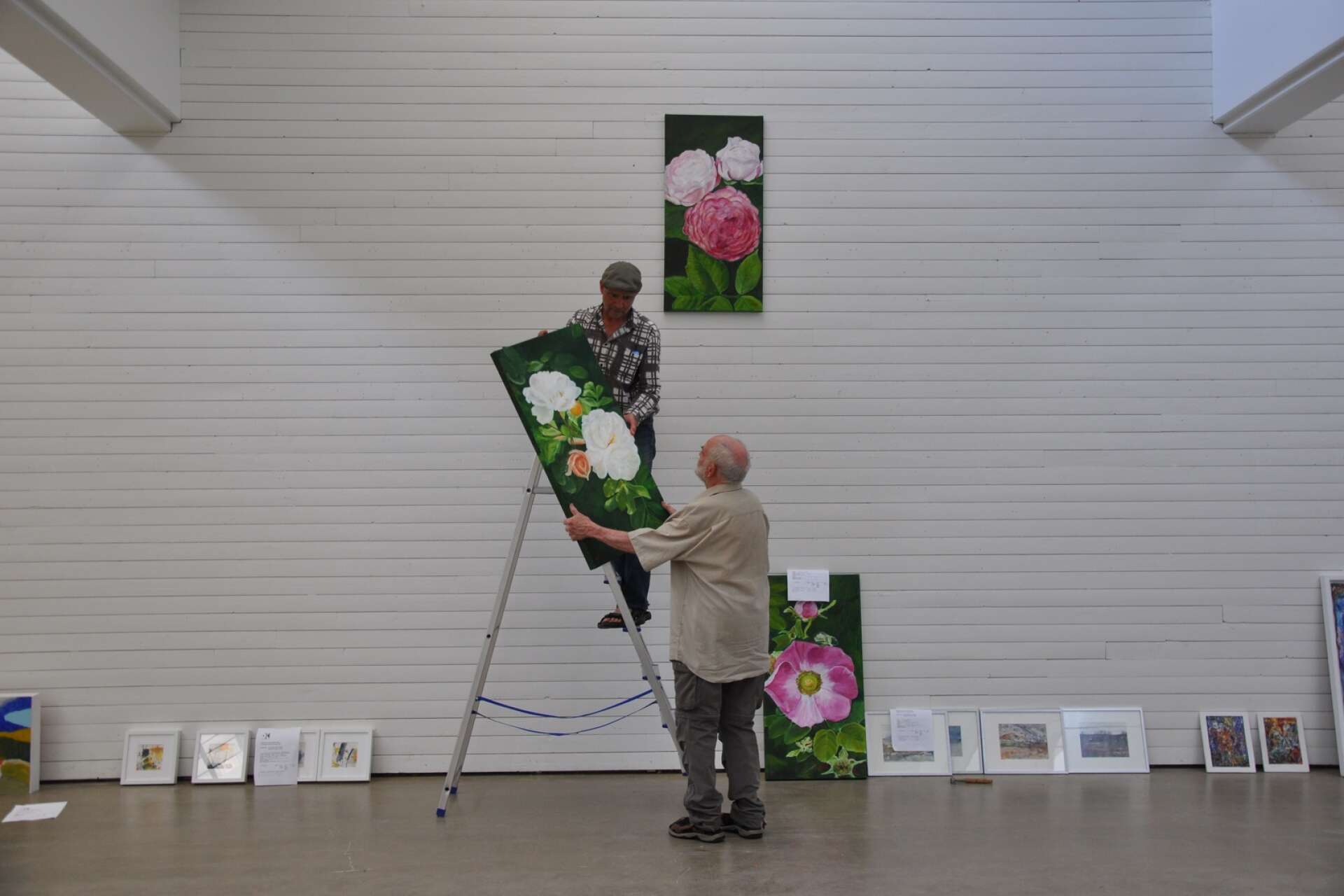 Martin Sjöberg och Walter Ruth påbörjar hängningen av tavlorna inför söndagens vernissage.