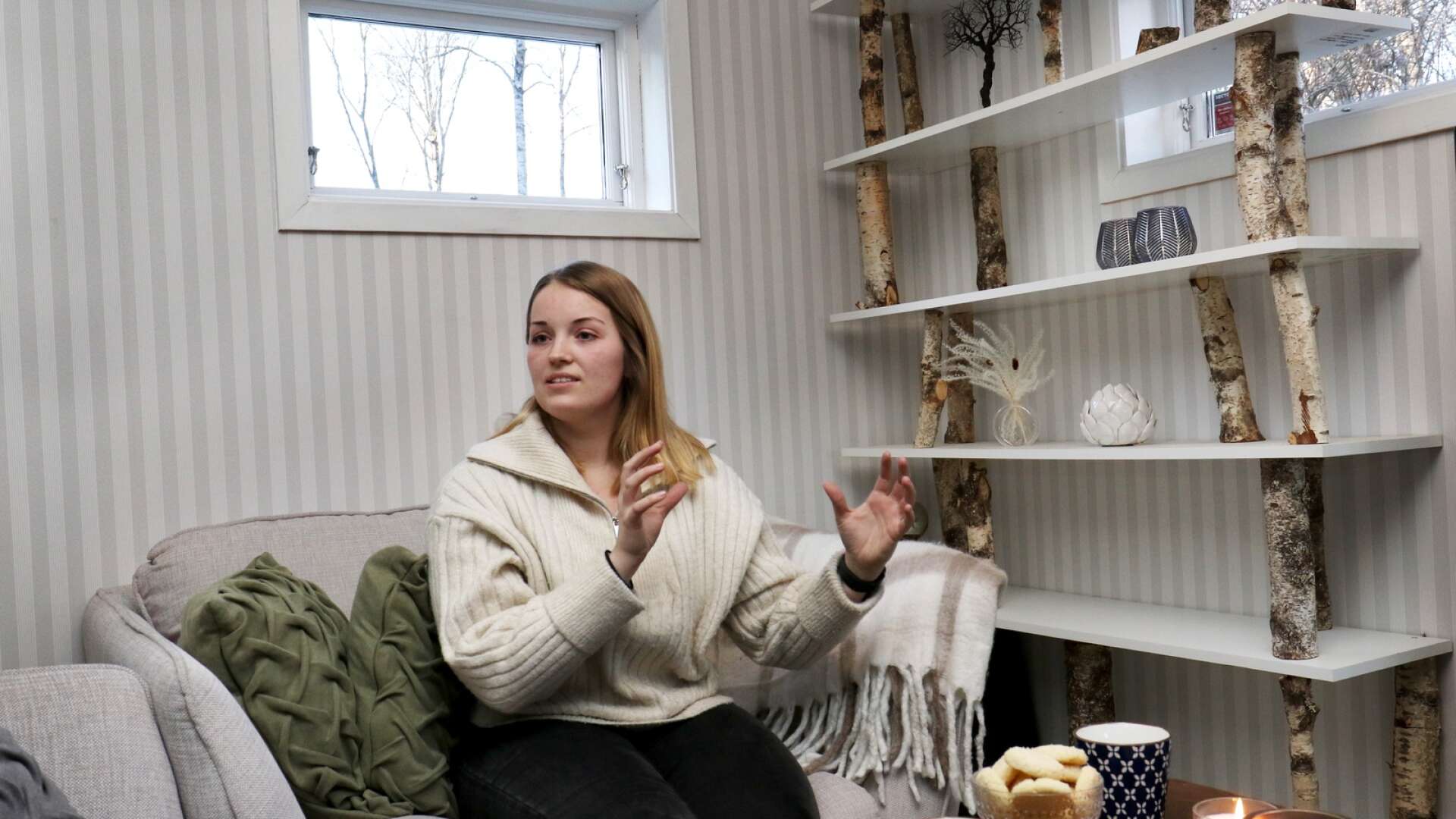 Hyllan bakom Elsa Gillsjö har hon byggt själv, med några hyllplan och träbitar ur föräldrarnas skog. ”Det är lite snett men det är det som är meningen, en sådan kan man inte köpa”, säger 25-åringen.