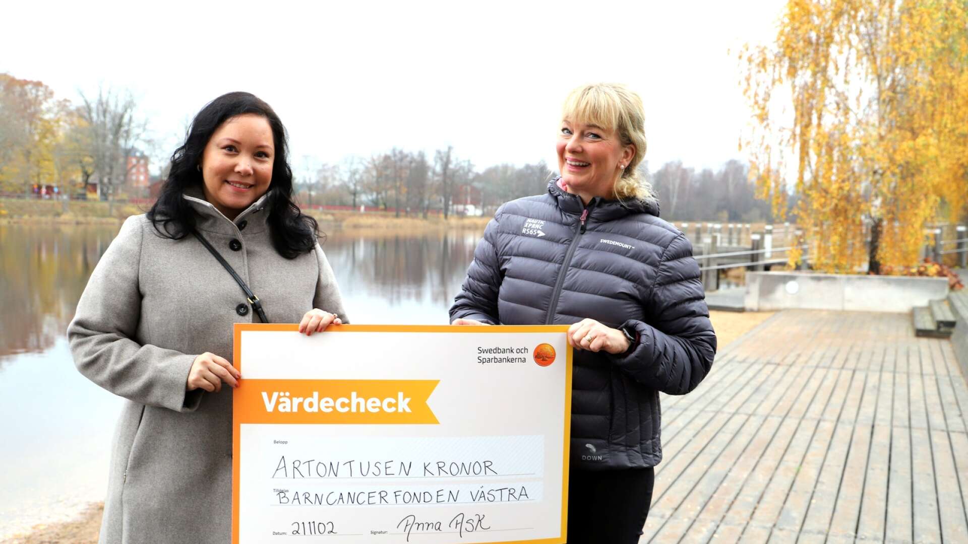 Anna Ask (i svart jacka) räcker över en check på 18 000 till Sara Güner från Barncancerfonden Västra.
