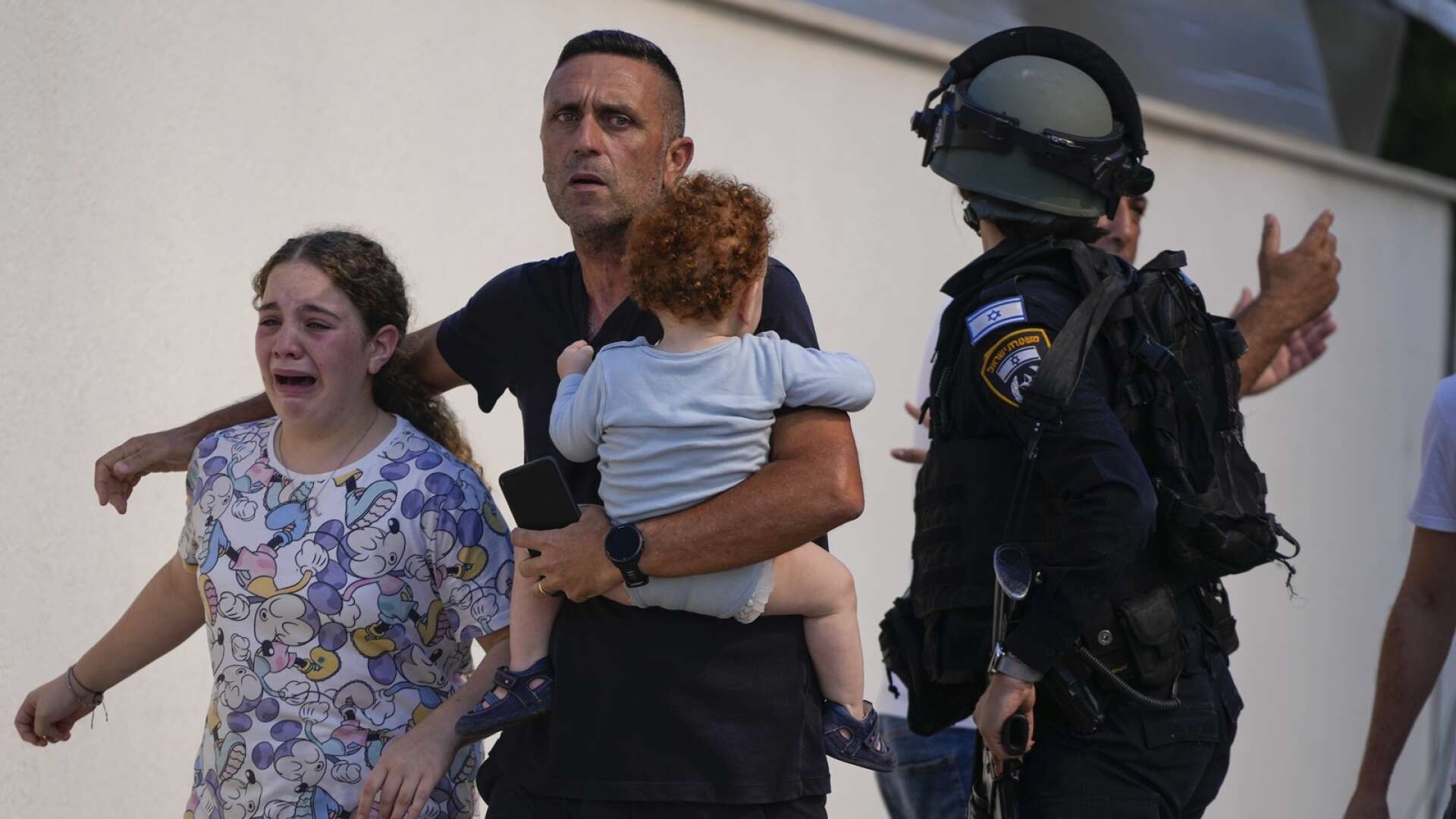 Israelisk polis evakuerar barn i Ashkelon under en palestinsk raketattack den 7 oktober.