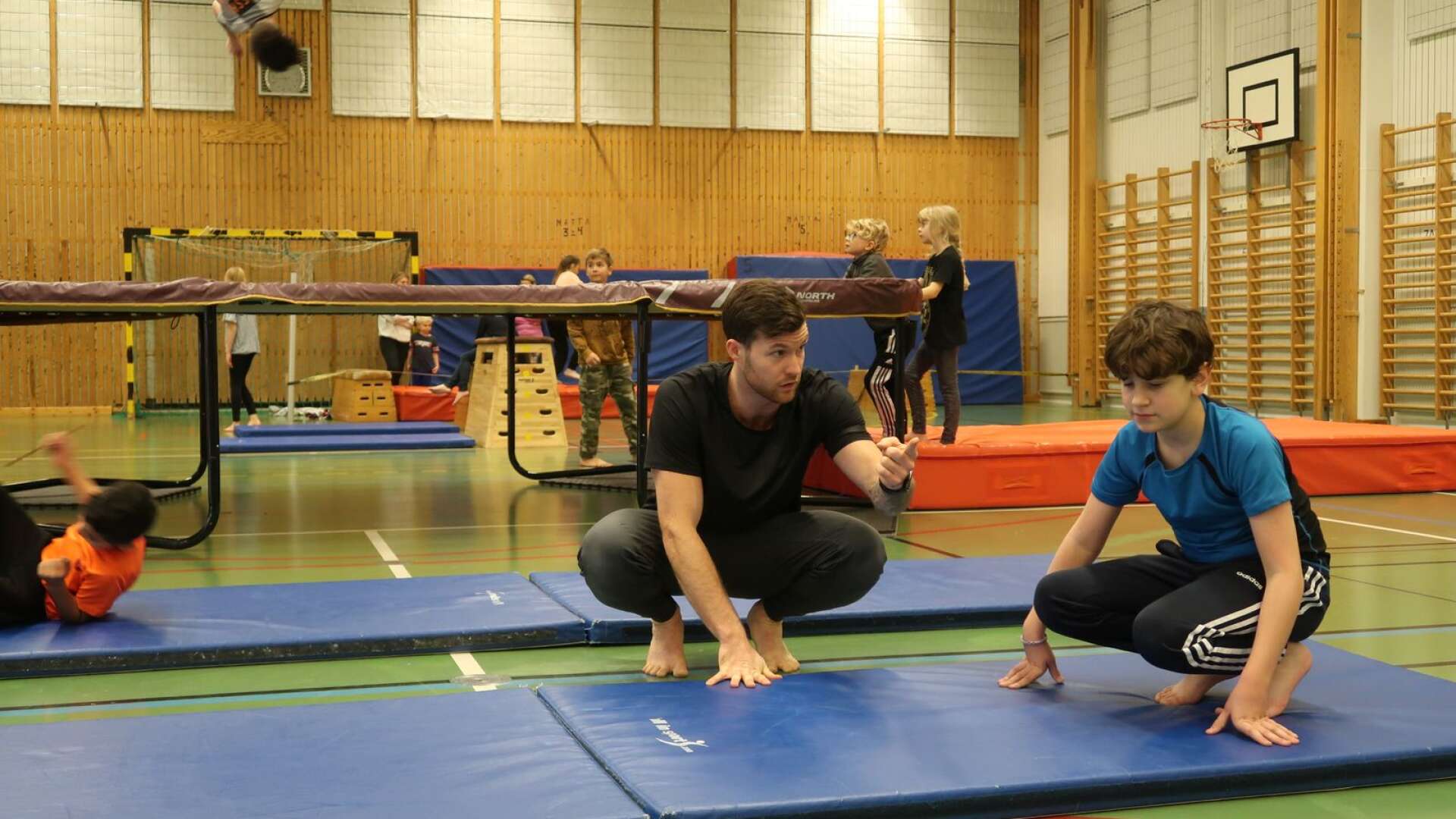Oskar Örn instruerar en av de unga deltagarna inför ett rullningsmoment. Notera killen på studsmattan högt uppe i luften uppe i bildens vänstra hörn!