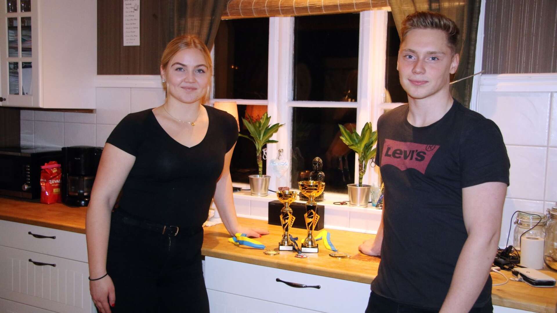 Alma Gustafsson och Emil Gustafsson har skördat en hel del framgångar under året. Här står de hemma i sitt kök i Filipstad med sina SM-guld och varsina defens-utmärkelser. Även Almas EM-medalj är med i samlingen.