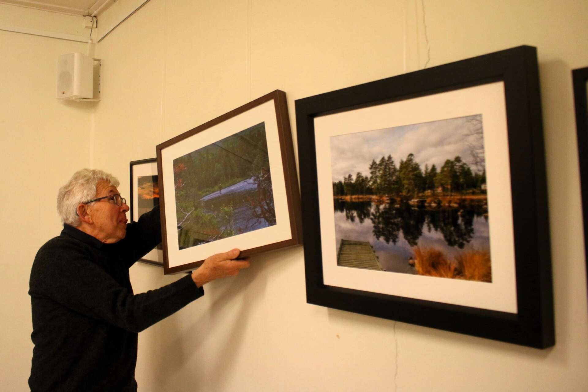 Göran Johansson är med och hänger upp tavlorna med bilder från Degerfors fotoklubb. 