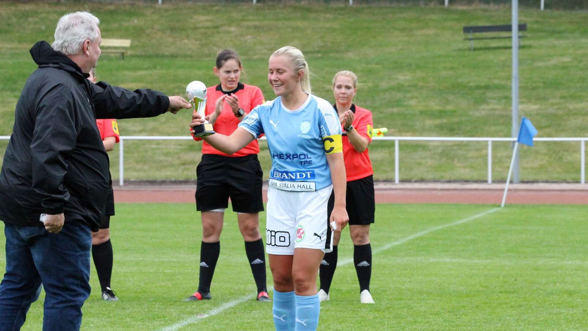 Vikens lagkapten Linnea Svanström tar emot segerpokalen från Johnny Gustavsson i Dalslands FF:s tävlingskommitté