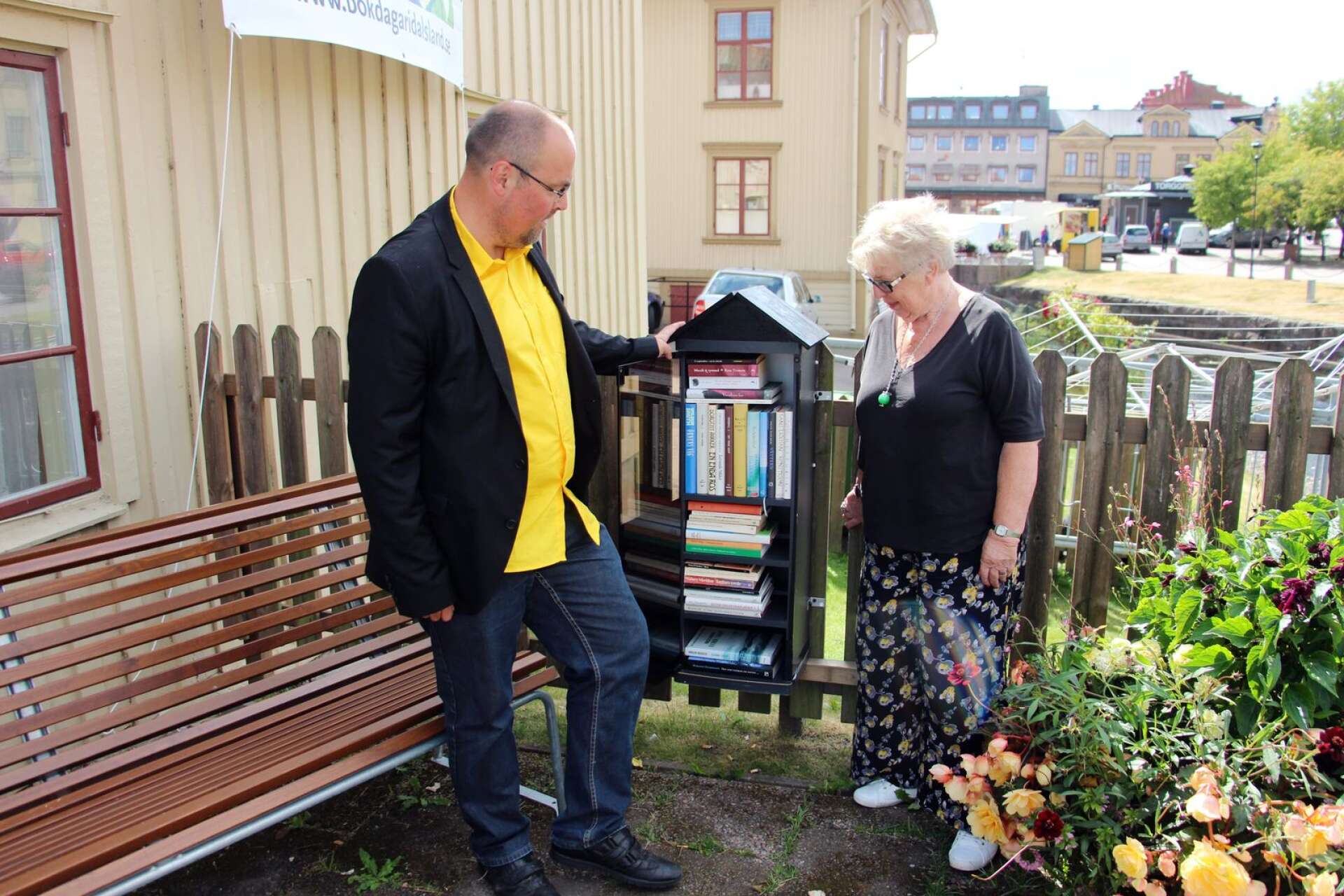 Victor Estby och Anita K Alexanderson vid invigningen av det första dalsländska bokskåpet i juli 2017. Det står på Ida Bäckmanns plats vid Fåfängebron på Kyrkogatan i Åmål. I sommar har litteraturföreningens frivilliga skött om elva skåp. 