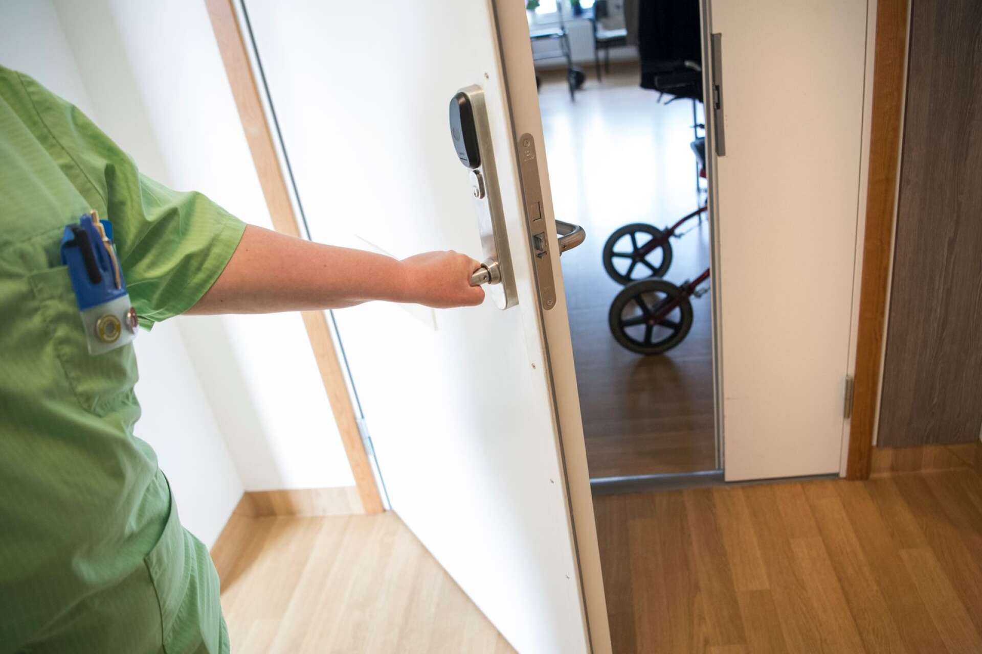 En undersköterska gläntar på en dörr till ett boende på ett äldreboende.
