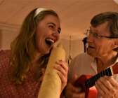Emelie använder kaveln som mikrofon medans pappa Lars-Inge spelar ukulele.