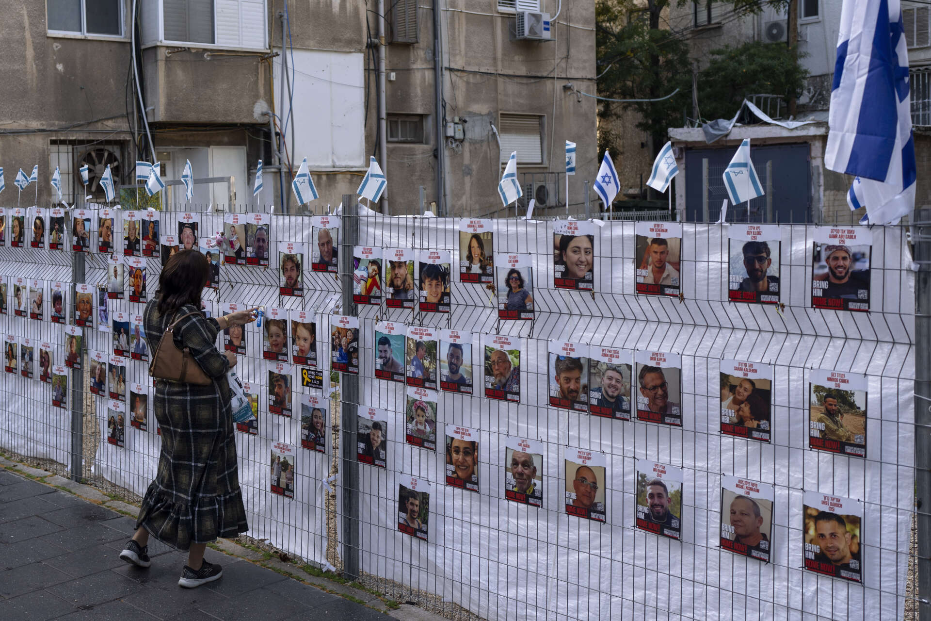 En kvinna tittar på bilder av gisslan som fördes bort den 7 oktober.
